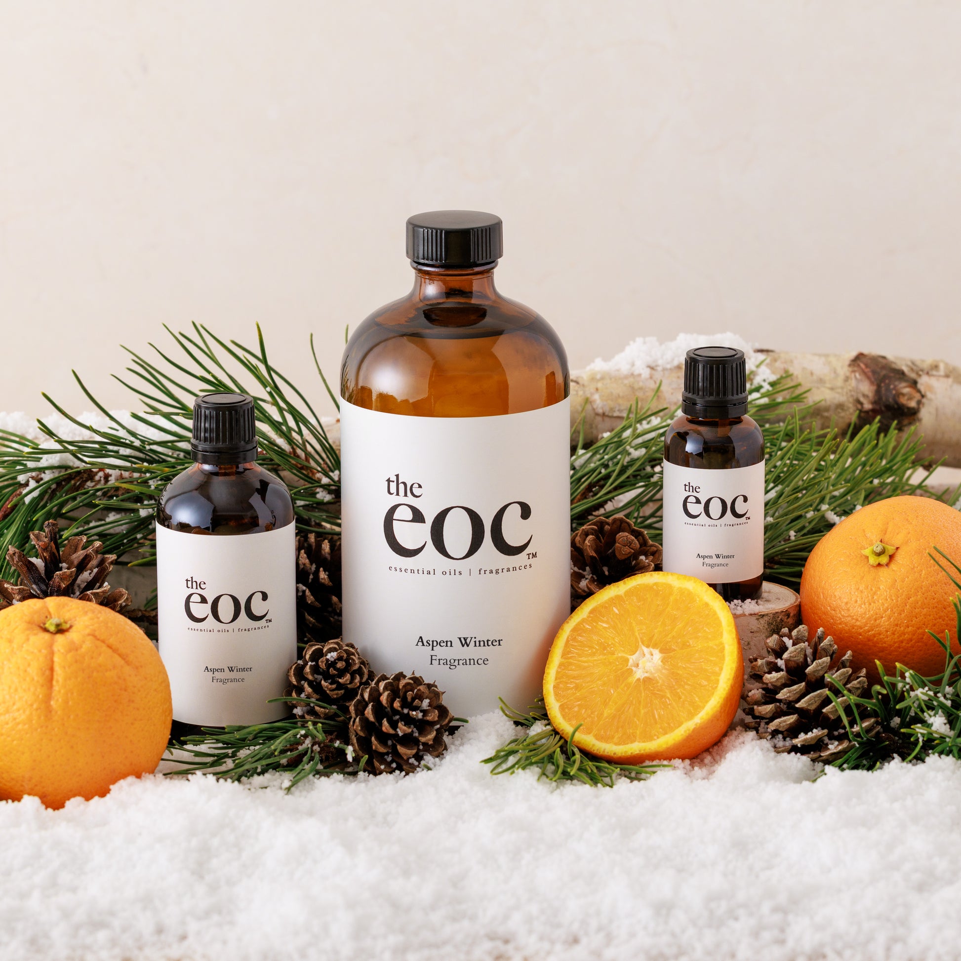 Bottles of 'the eoc' with oranges and pine cones on a snowy background