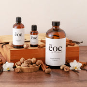 Three bottles of 'the eoc' fragrances on a wooden surface with nuts and cinnamon sticks.