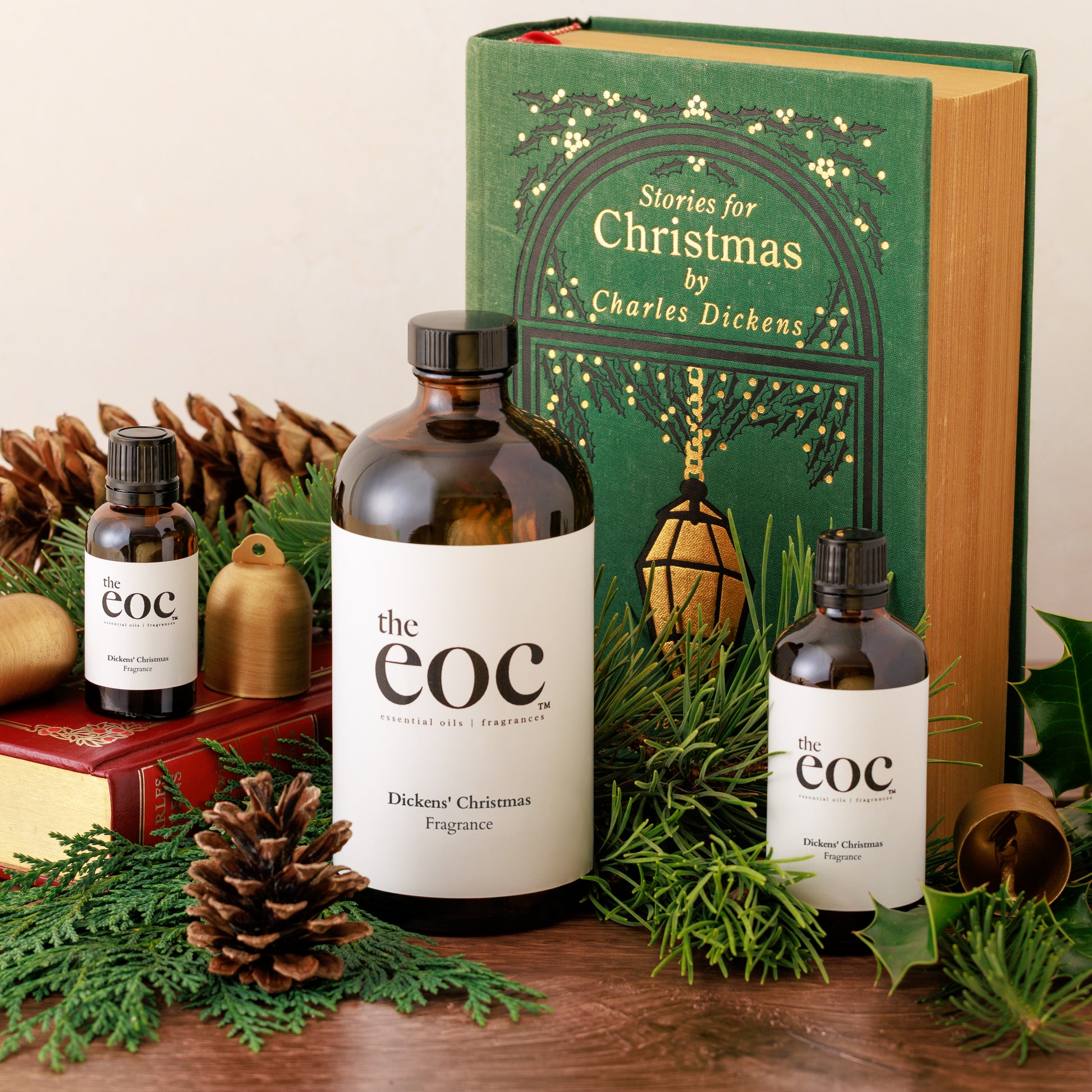 Three bottles of 'the eoc' Dickens' Christmas fragrance with a book titled 'Stories for Christmas by Charles Dickens' on a decorative background.