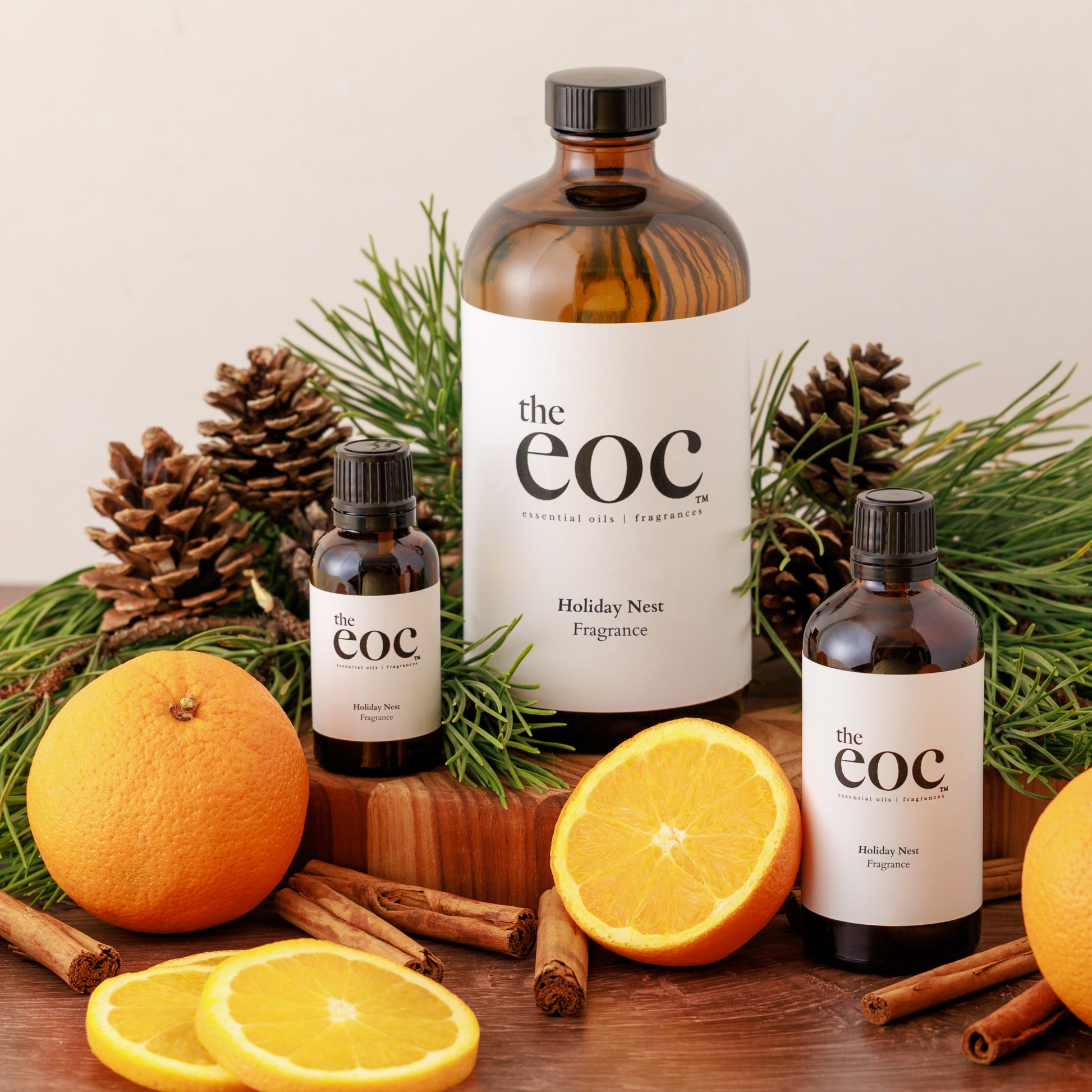 Fragrance bottles with 'the eoc' branding on a wooden surface with oranges and pine cones.