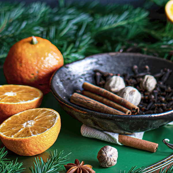 Spices and oranges on a green surface with a decorative background