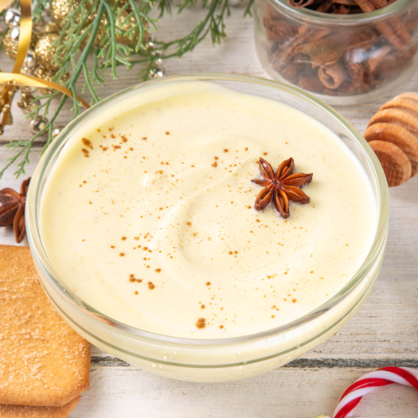 Glass of eggnog with a star anise garnish on a festive background